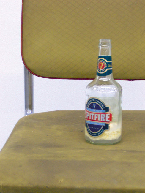 installation (Stuhl, Beton, DVD-Fernbedienung, Bierflasche, Rahm, Legende) detail